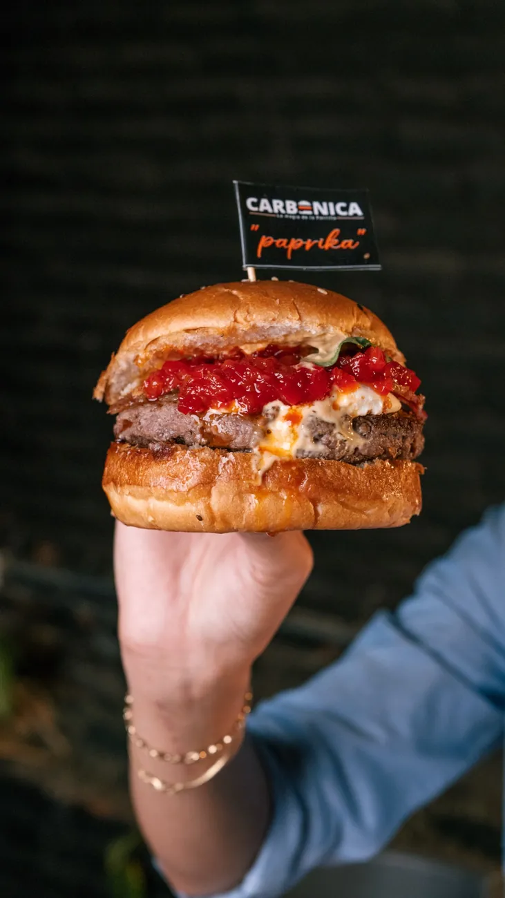 Cliente disfrutando una Paprika Burger de Carbónica recién servida